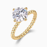 Round moissanite solitaire set in prongs on yellow gold beaded ring band, side view