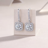 Pair of cushion halo drop earrings with prong-set center stone and pavé halo, white gold