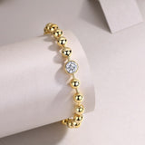 Bezel-set round moissanite stone on gold bead bracelet with toggle clasp detail
