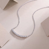 Curved bar moissanite smile necklace close-up with evenly spaced round stones