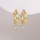 Round moissanite drop hangs from chunky gold hoops, yellow gold vermeil