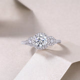 Round halo cluster ring with prong-set center and pear-shaped side stones