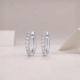 Single-row moissanite huggie hoops with shared prong bezel, bright stone row