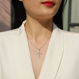 Moissanite cross pendant necklace with round stones on fine chain, worn at neckline