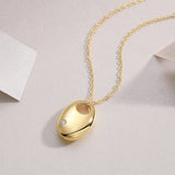 Oval dome pendant necklace with yellow gold tone finish and small round moissanite stone