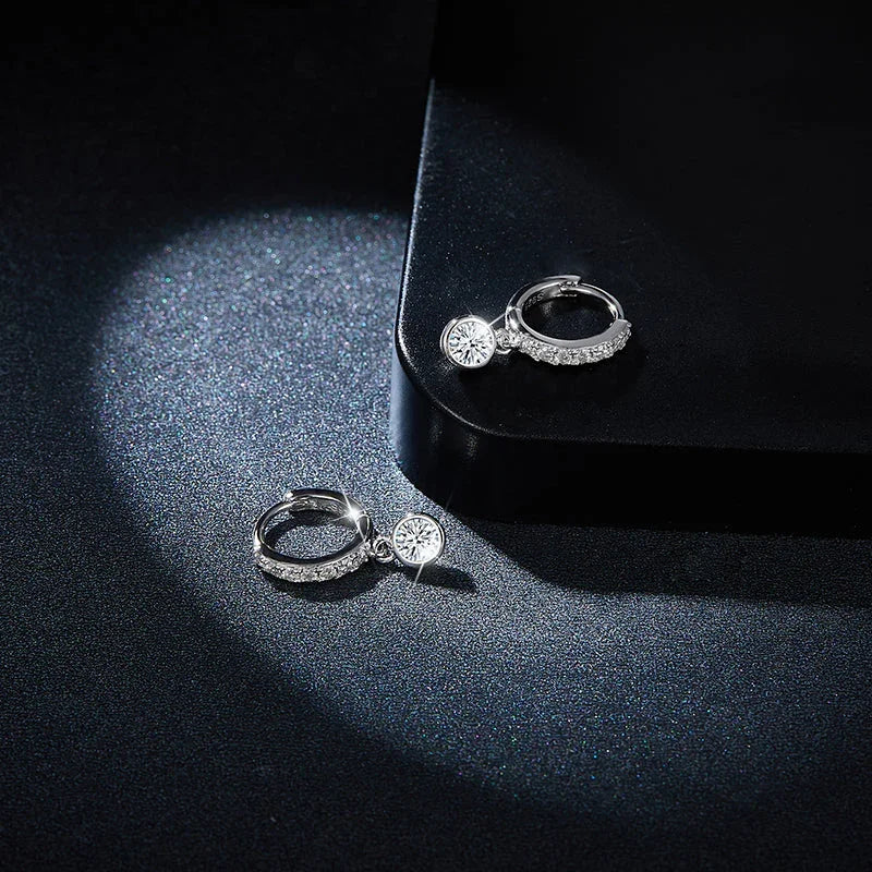 Close view of round moissanite drop charm on pavé huggie hoop