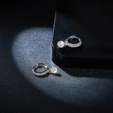 Close view of round moissanite drop charm on pavé huggie hoop