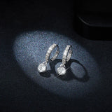 Huggie hoop earrings with pavé bezel band and round dangling moissanite
