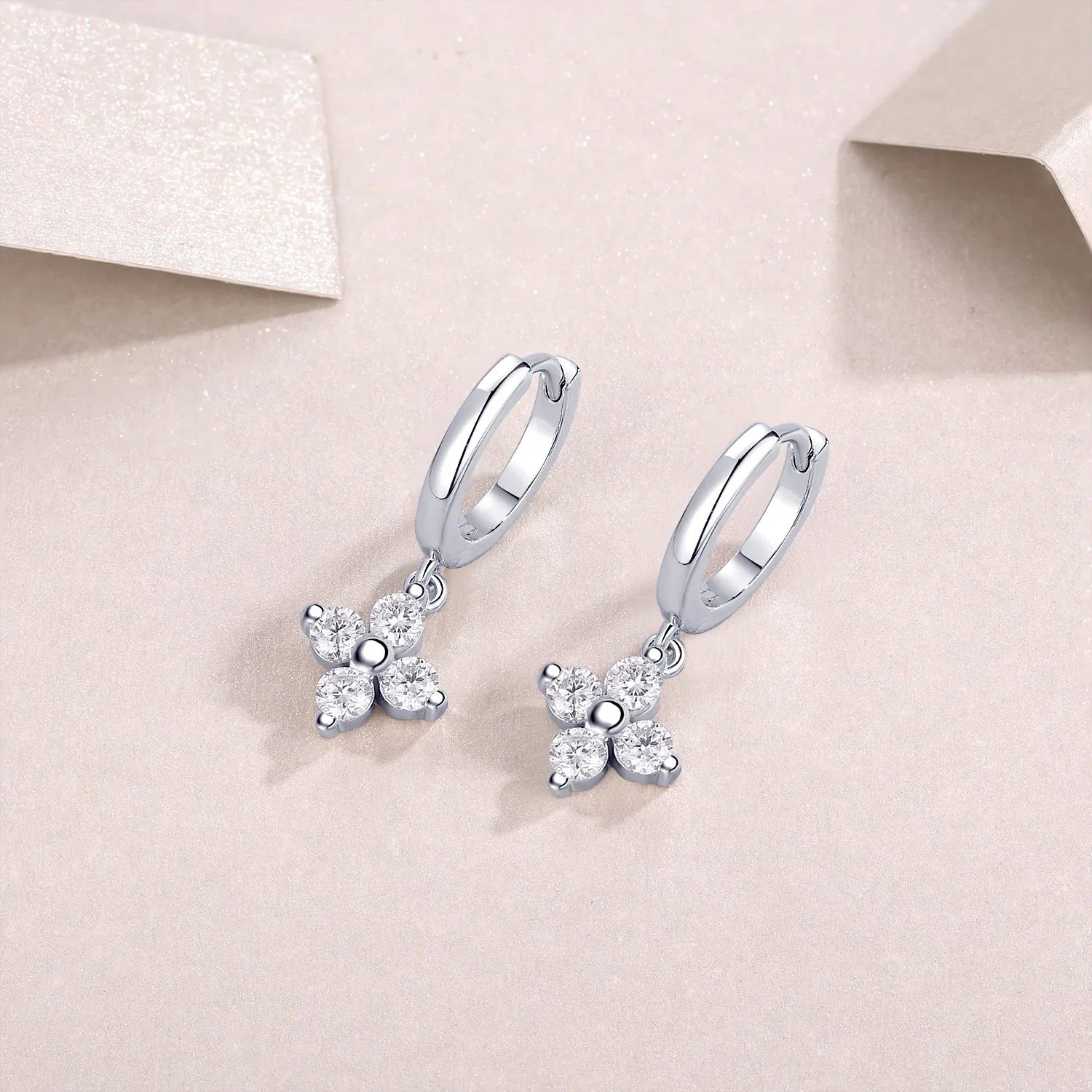 Silver-tone huggie hoop earrings with dangling four-petal flower moissanite