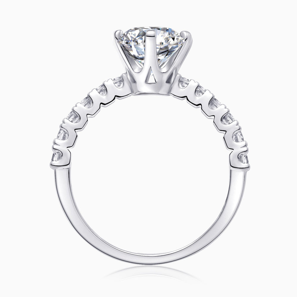 Top close-up of round moissanite ring, prong setting and pavé band details