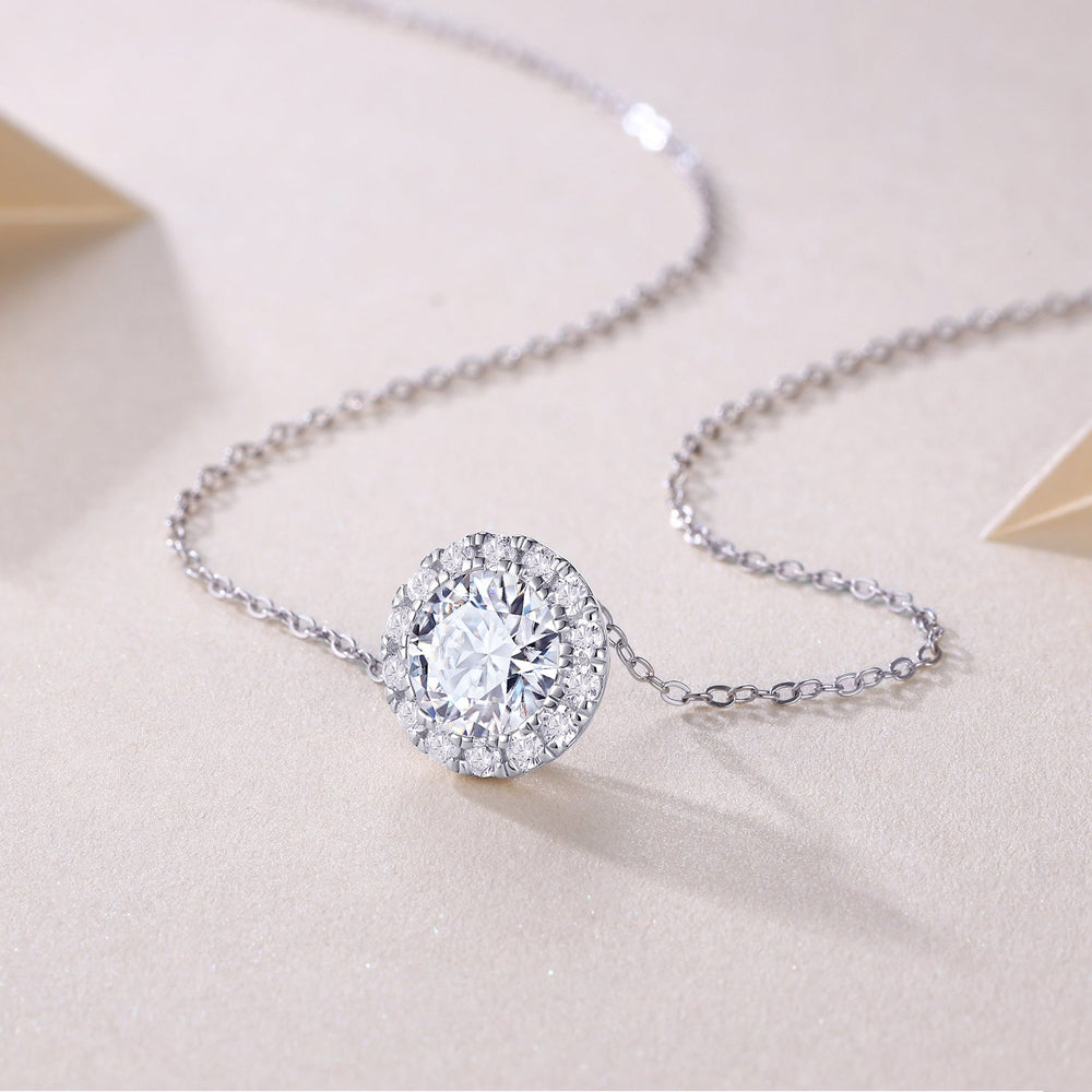 Close-up of round halo moissanite pendant on fine chain with pavé sparkle stones
