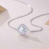 Close-up of round halo moissanite pendant on fine chain with pavé sparkle stones