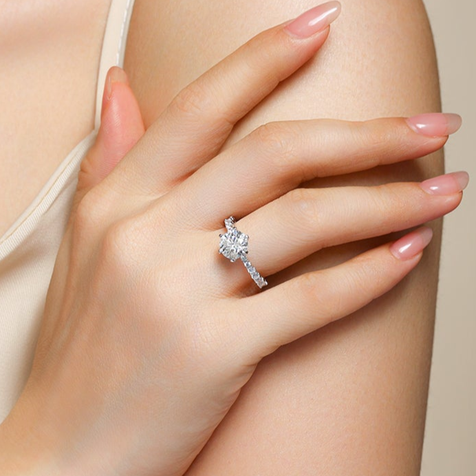 Round moissanite pave wedding ring on hand, white metal band and prong-set center