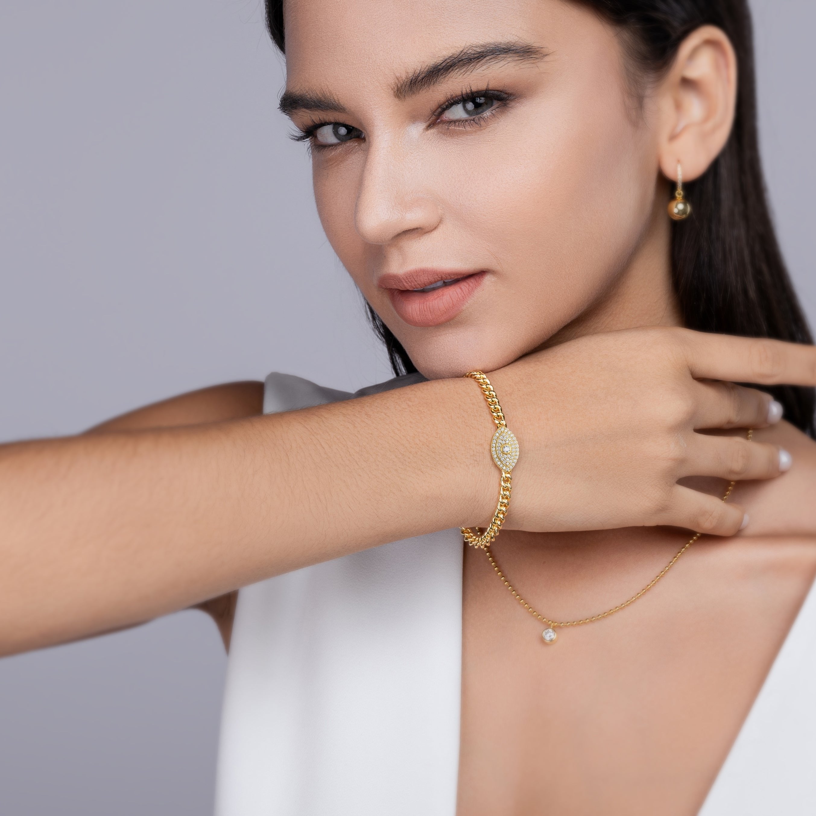 Evil-eye Cuban link bracelet in yellow gold vermeil on wrist, sparkling oval charm