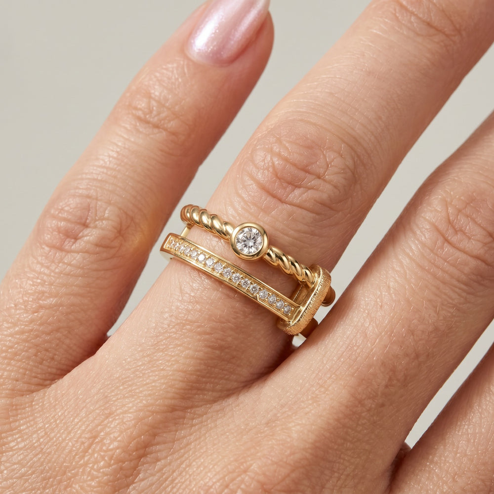 Close-up of double-band ring: twisted rope detail, pavé row, and round stone, yellow gold