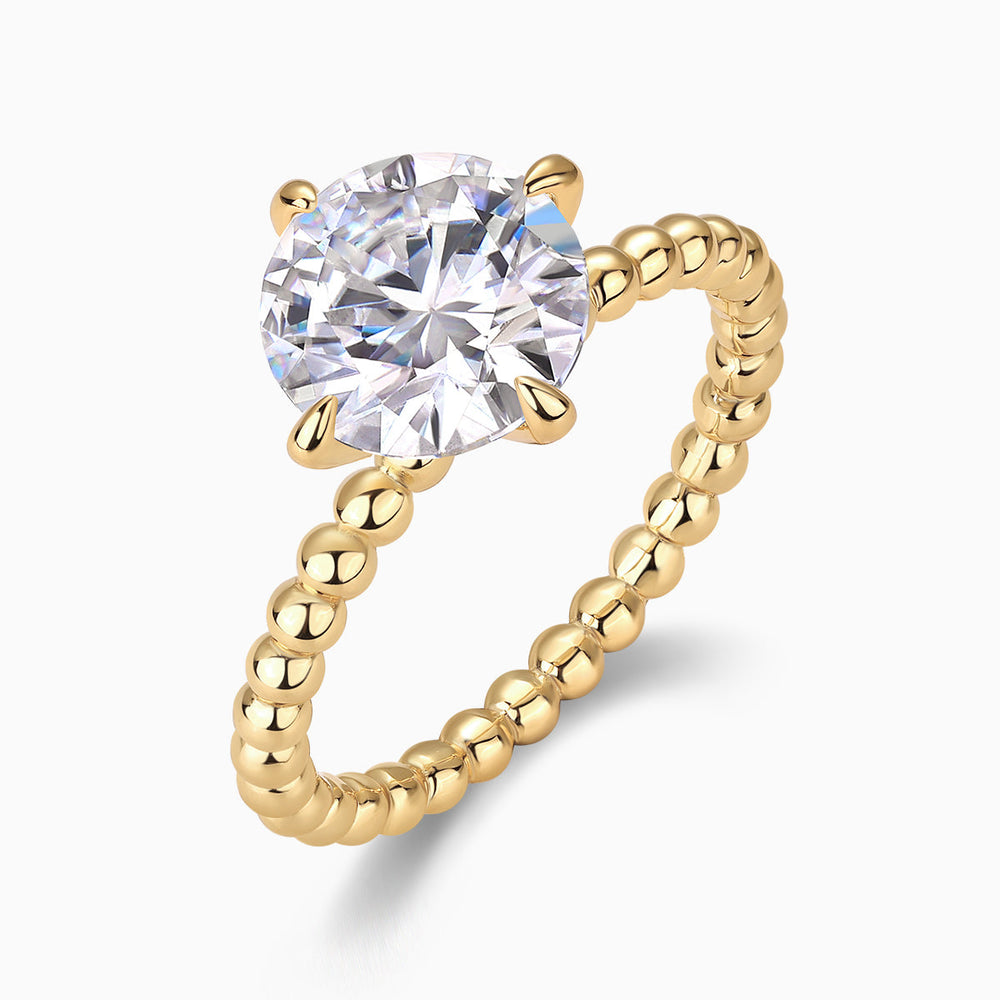Round moissanite solitaire set in prongs on yellow gold beaded ring band, side view
