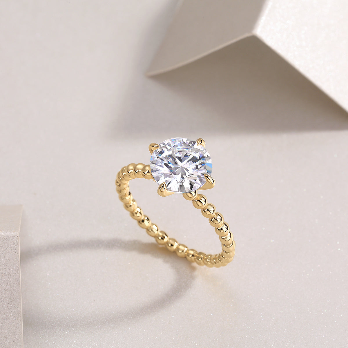 Angle view of yellow gold plated solitaire ring with round moissanite center and beaded band