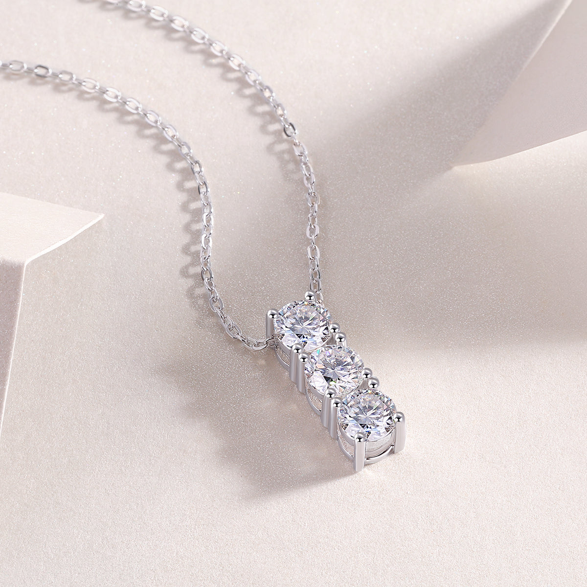 Close-up: three-stone vertical bar moissanite pendant on silver-tone chain