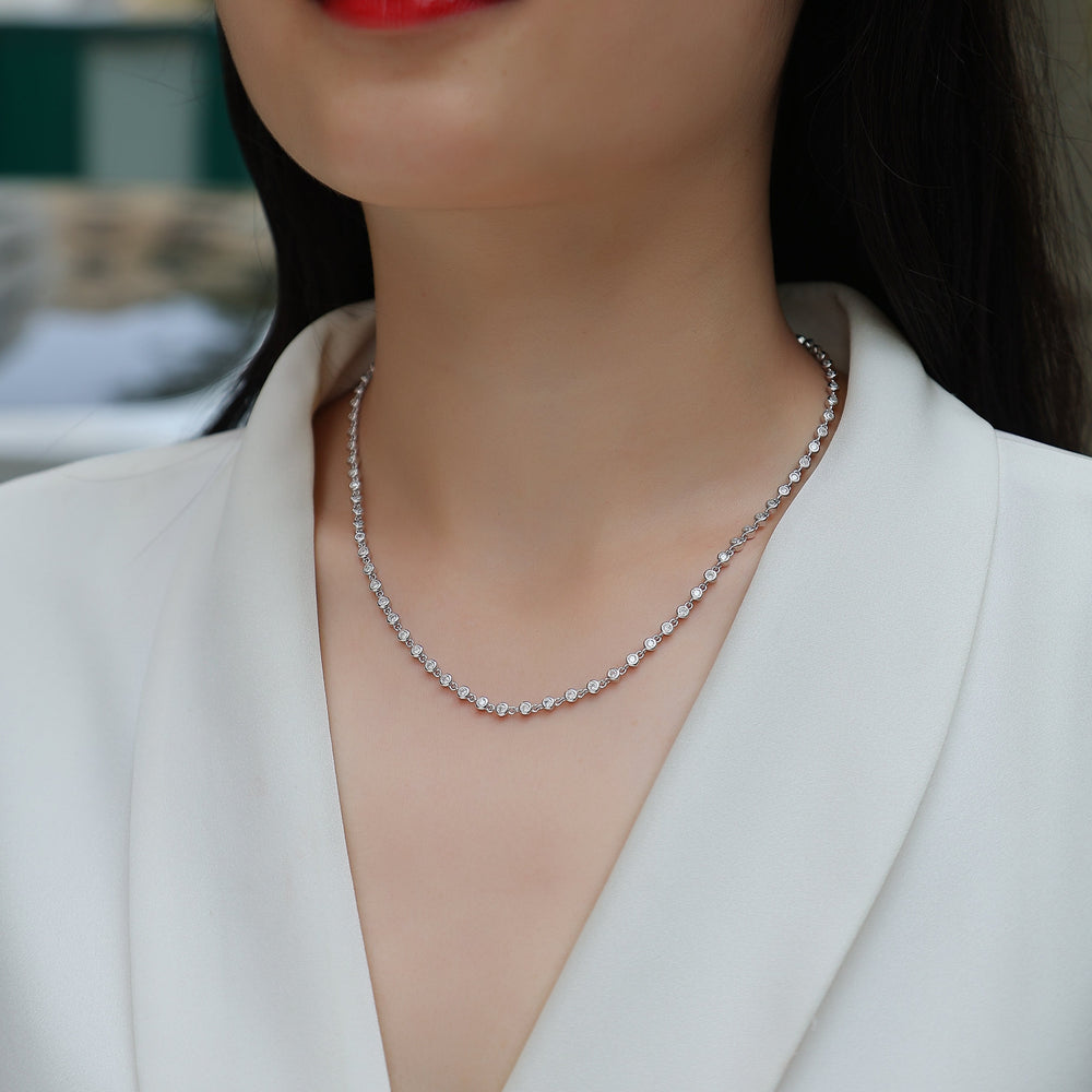 Moissanite tennis necklace worn at collarbone, white gold vermeil with round bezel stones