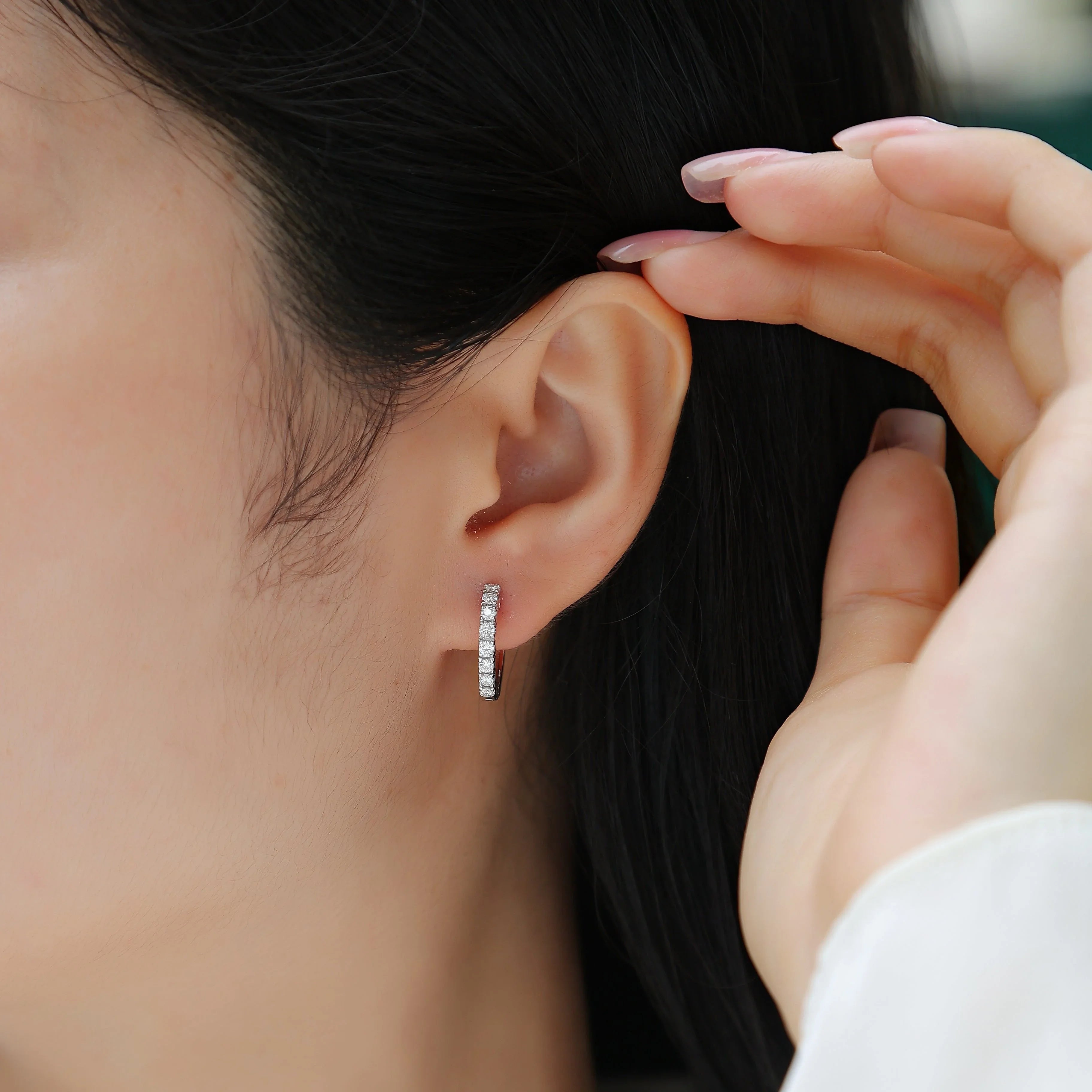 Moissanite huggie hoop earring on ear, single row shared-prong setting, white gold tone