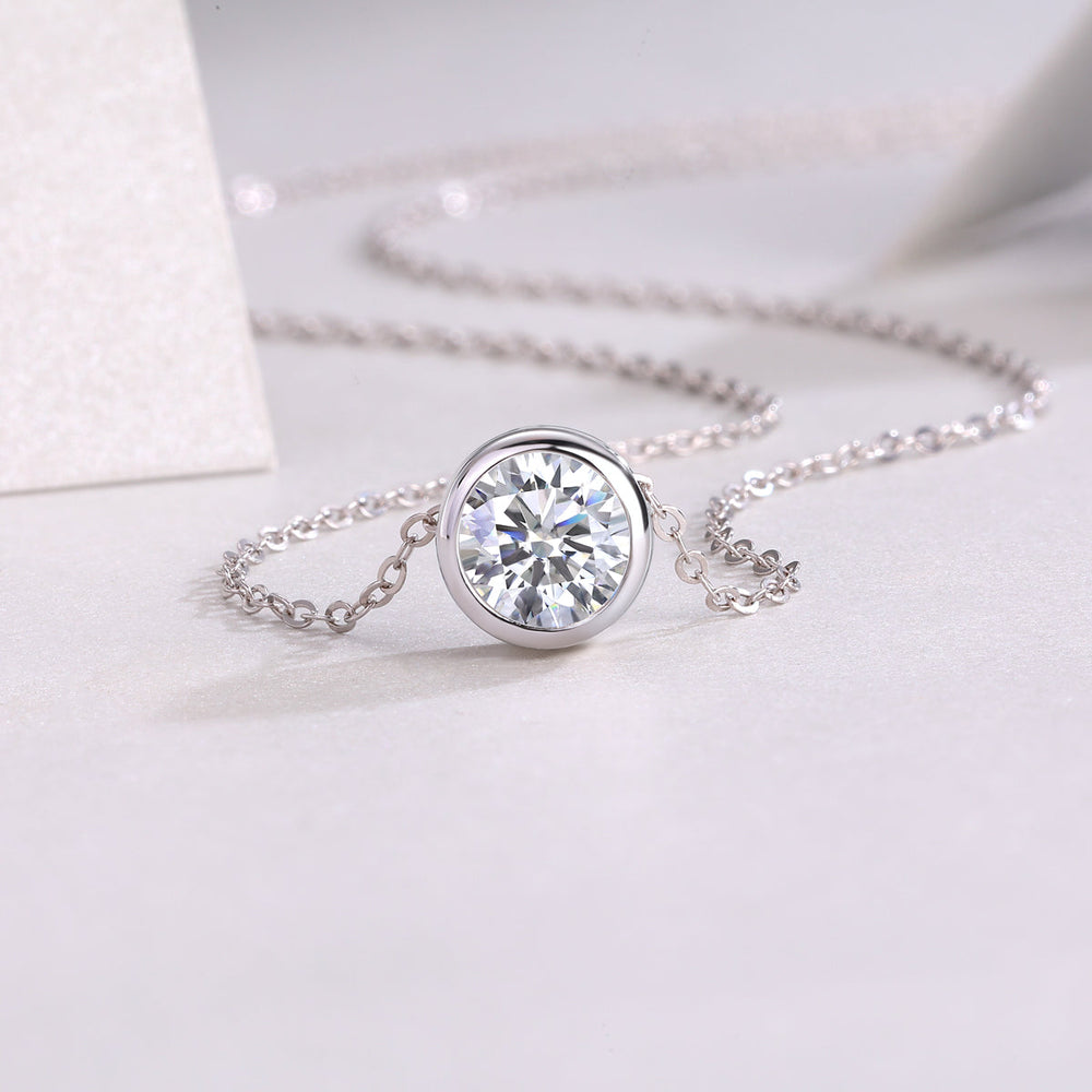 Round bezel-set moissanite solitaire pendant centered on a delicate chain