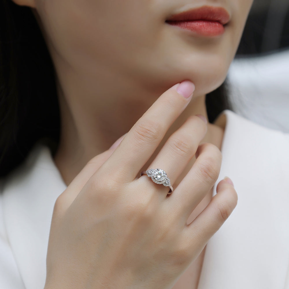Moissanite halo engagement ring on finger, round center stone with sparkling side halos