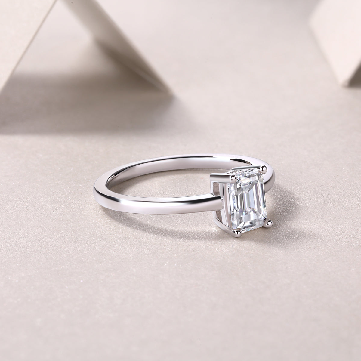 Solitaire emerald-cut moissanite ring, side view of band and prong setting