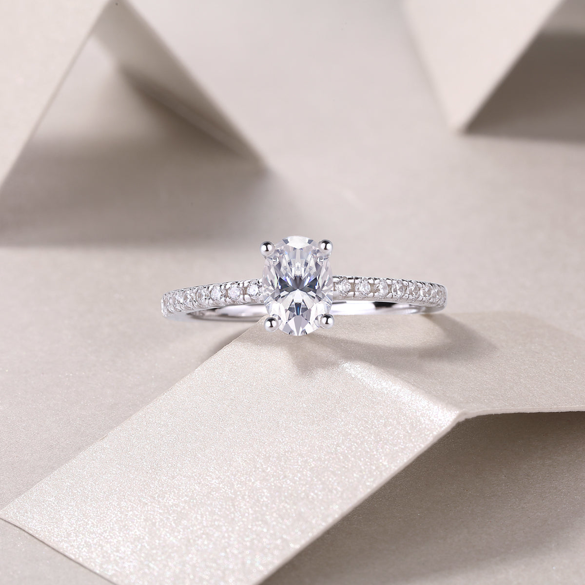 Oval-cut moissanite engagement ring featuring pavé side band and round prong tips