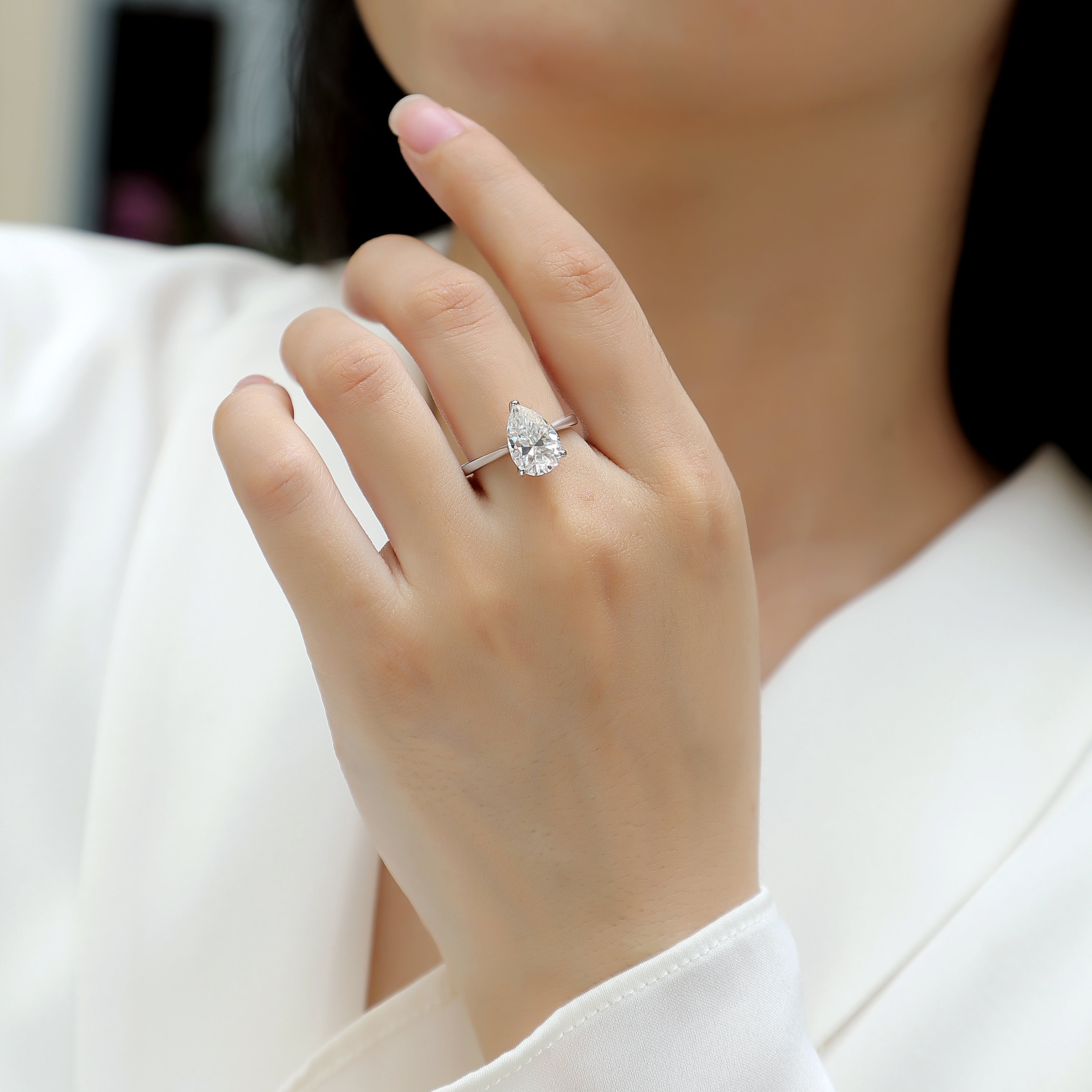 Pear-cut solitaire moissanite ring on hand, white gold vermeil band
