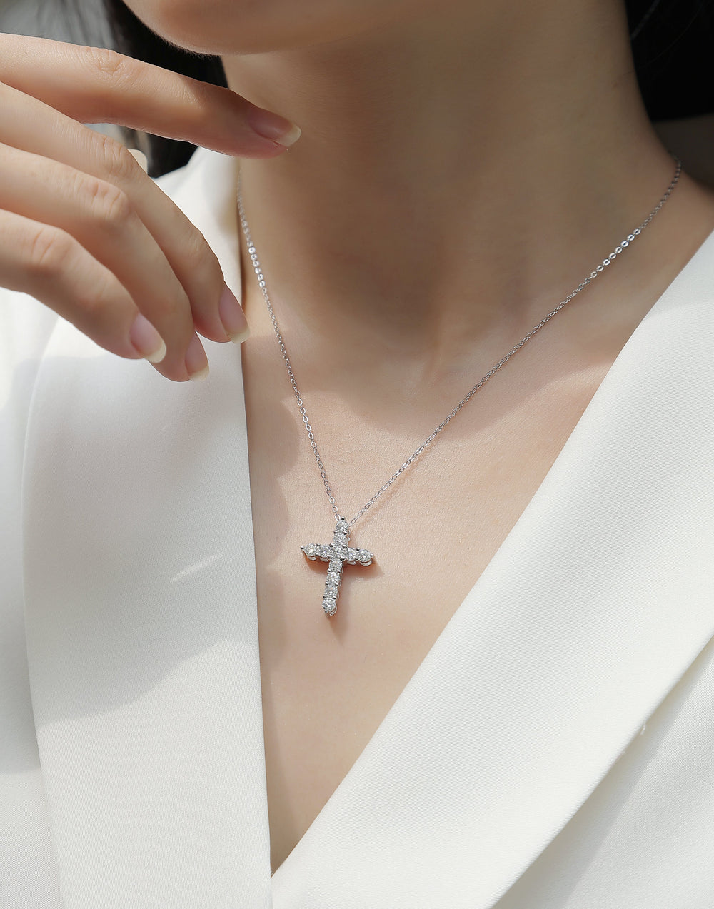 White metal cross pendant necklace with round moissanite stones on a fine chain
