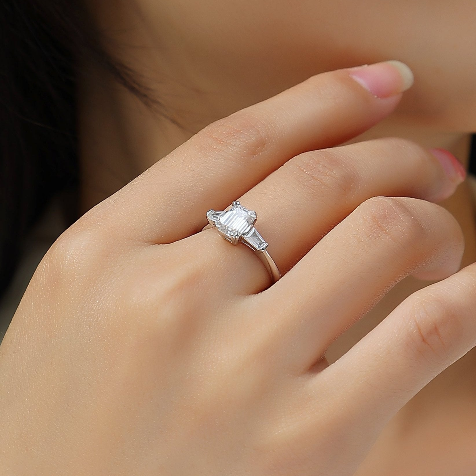 Rose gold vermeil three-stone emerald-cut moissanite ring on hand with square stones