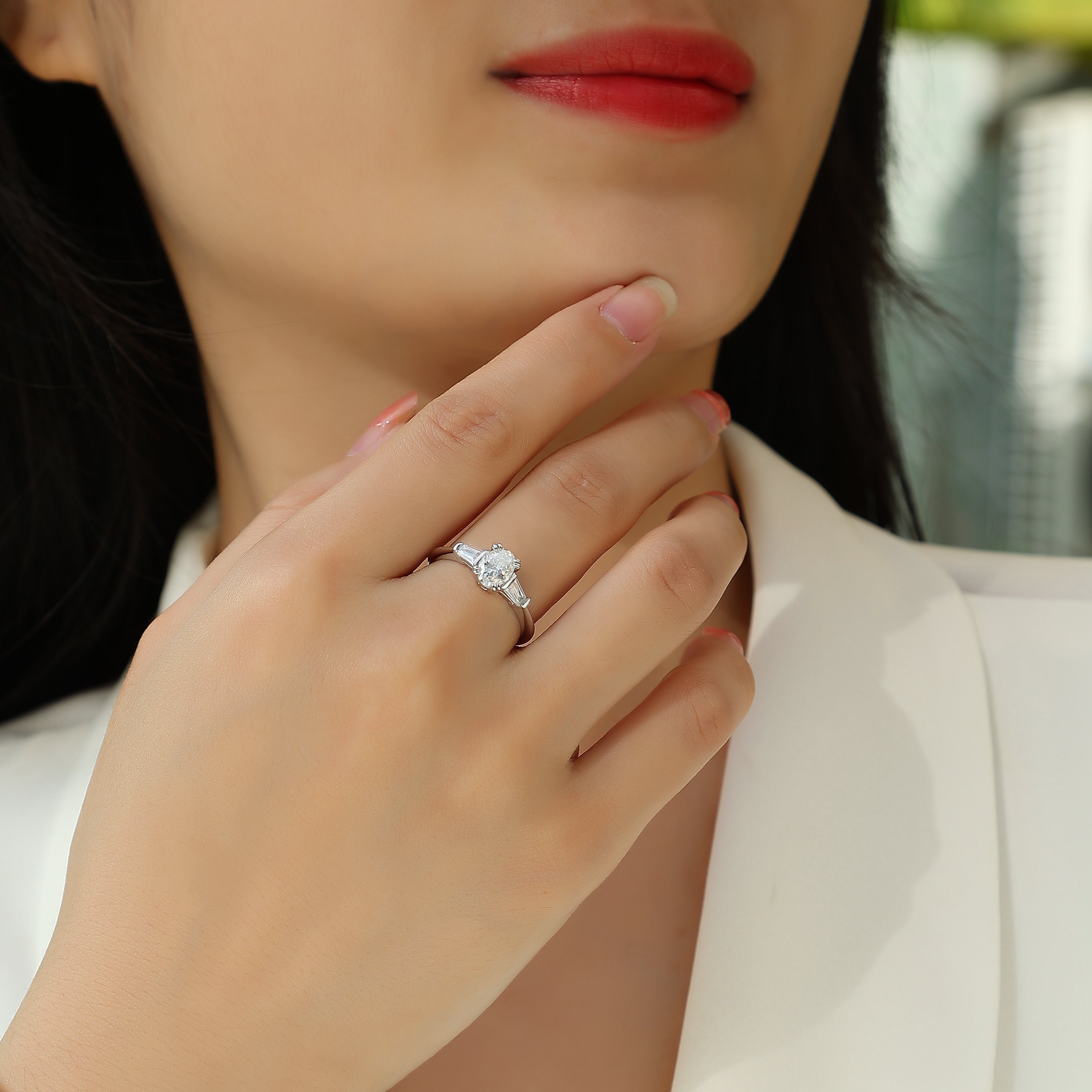 Ring on finger: oval moissanite center with baguette side stones, white gold band