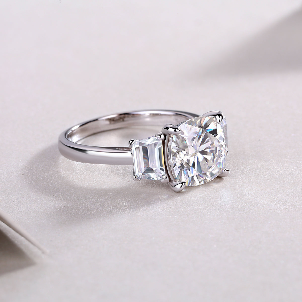 Three-stone cushion-cut moissanite ring in profile with side baguette stones