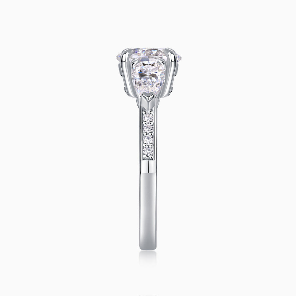 White gold-plated three-stone moissanite ring, prong-set round center stone with pavé shank