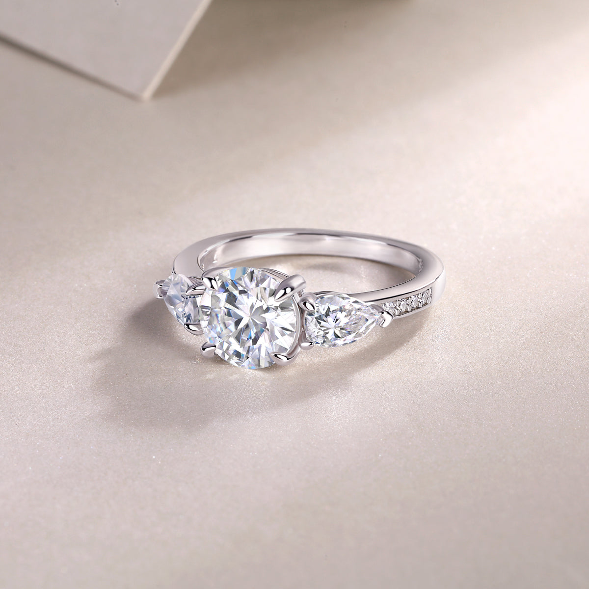Three-stone moissanite ring, white gold-plated band with pavé detail on the shoulders
