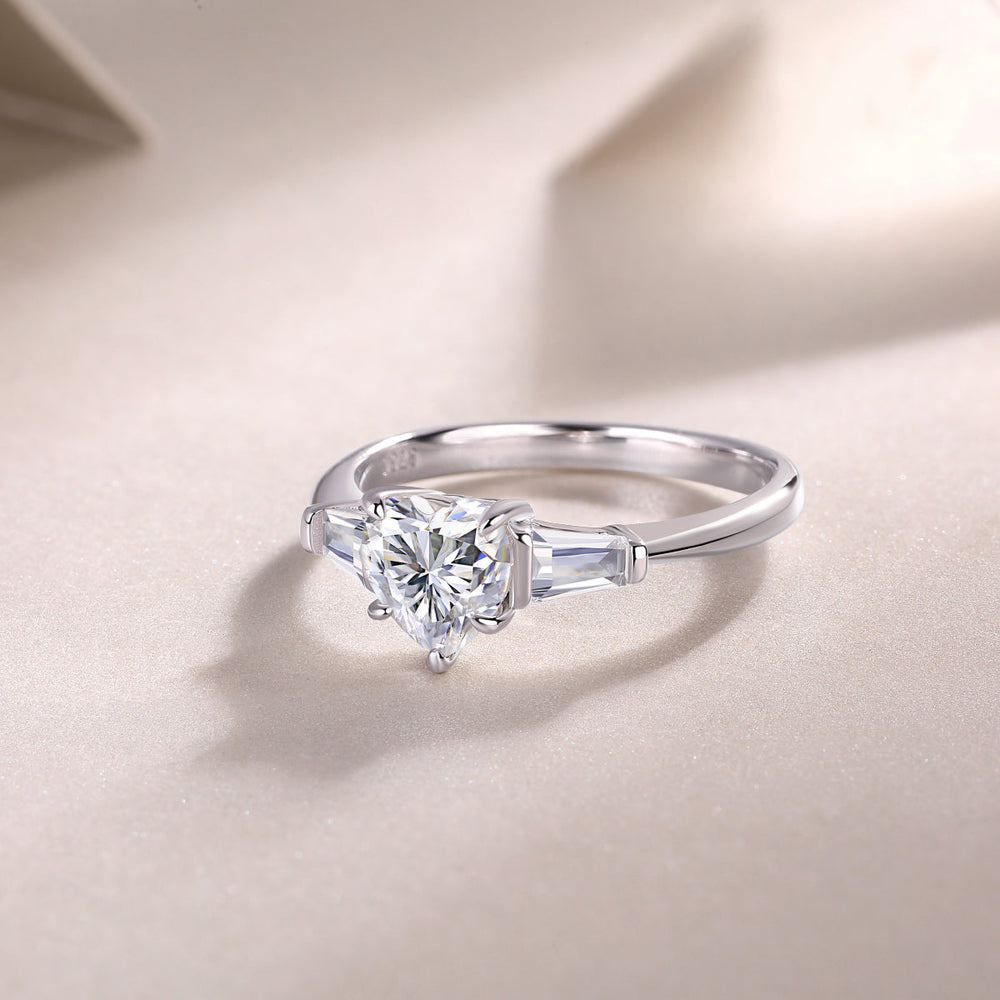Three-stone moissanite ring angled view, heart-cut center with baguette side stones