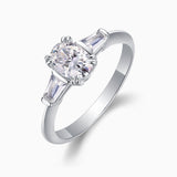 Angle view: oval center moissanite with baguette side stones, three-prong setting