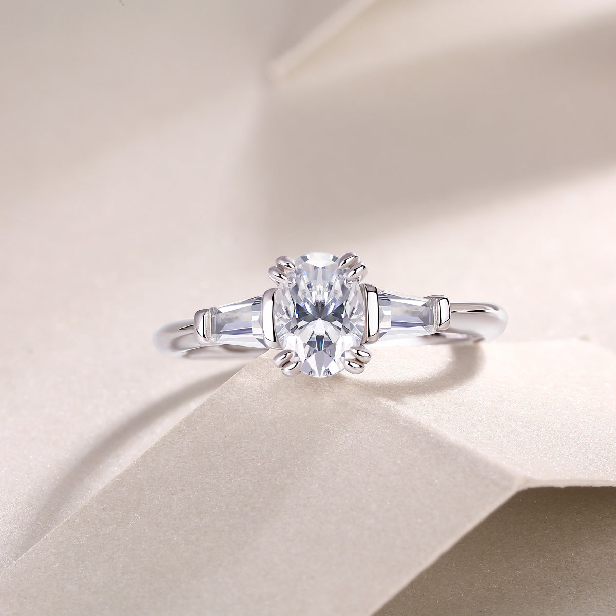 Three-stone oval moissanite ring, central oval with baguette side stones in white gold