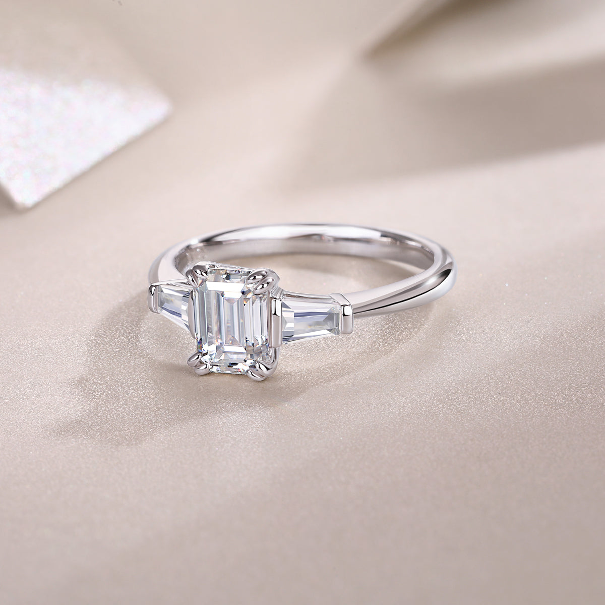 Three-stone emerald-cut moissanite engagement ring, white gold vermeil, side profile view