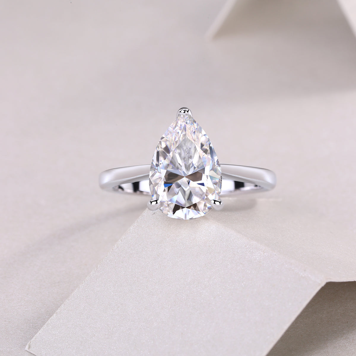 White gold vermeil pear-cut solitaire moissanite ring, front view of four-prong setting