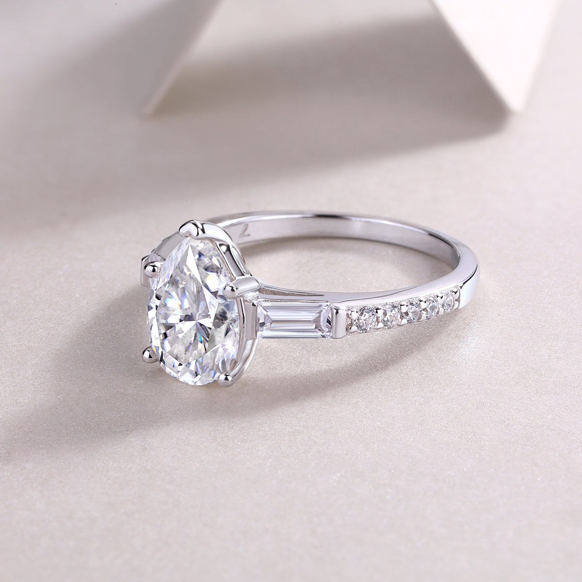 Pear-cut moissanite ring with baguette side stones and pavé row on white gold band
