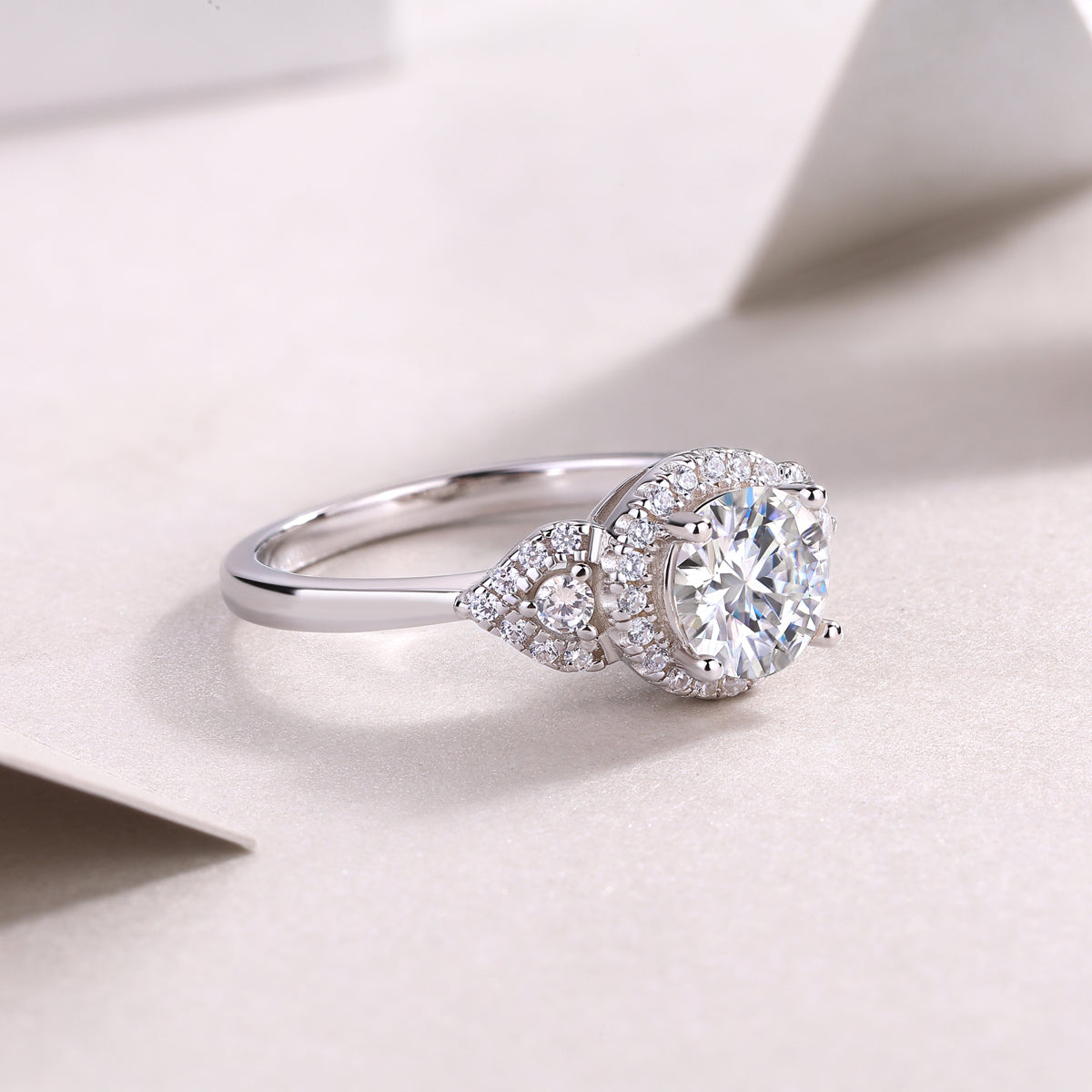 Round center moissanite with sculpted halo and pavé stones on white gold band