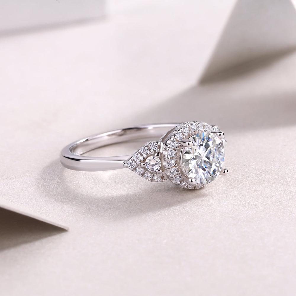 Round center moissanite with sculpted halo and pavé stones on white gold band