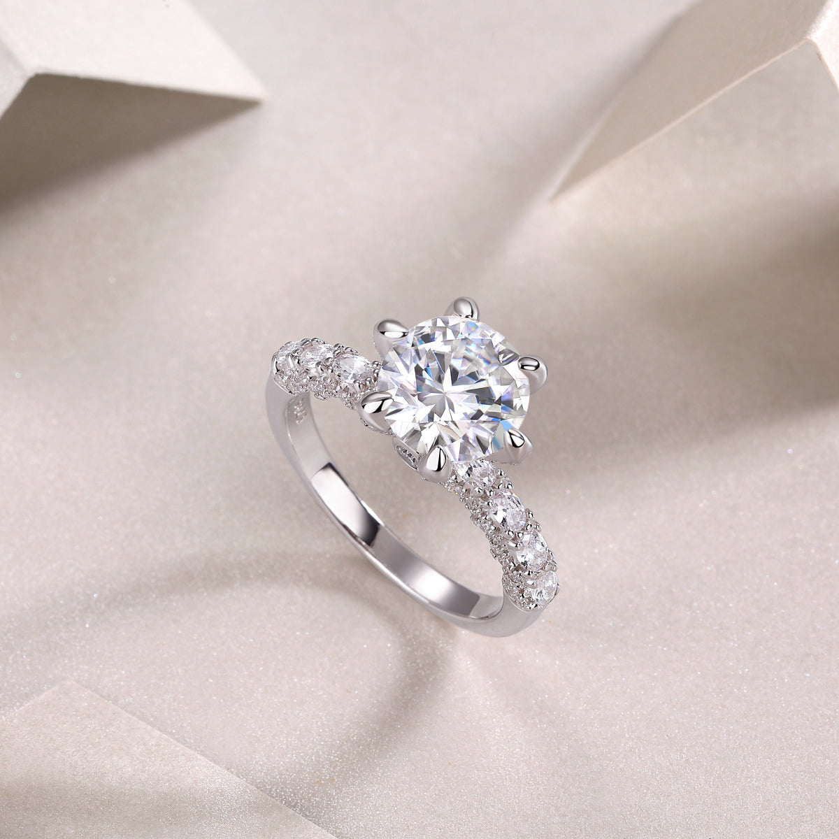 Angled view of six-prong pavé moissanite engagement ring with round center stone