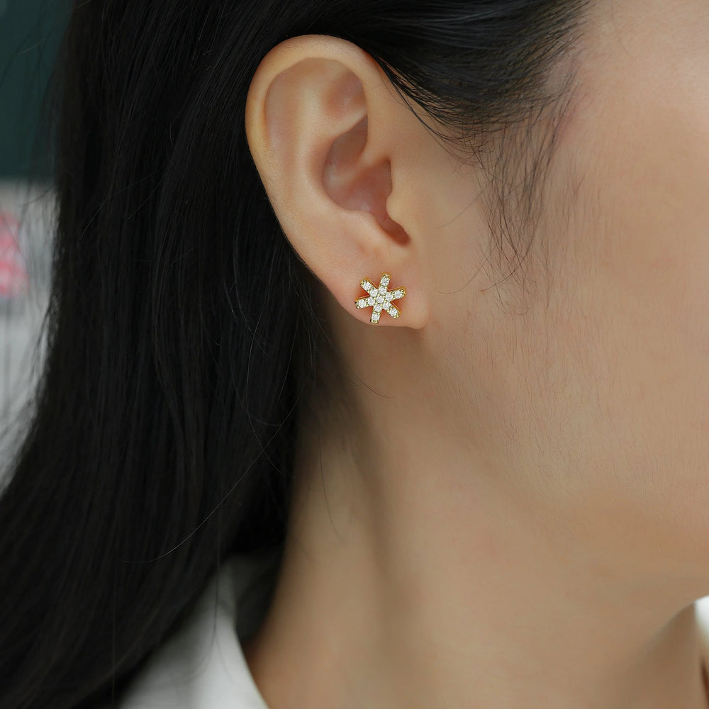 Snowflake stud earring on ear, yellow gold vermeil with white moissanite sparkle
