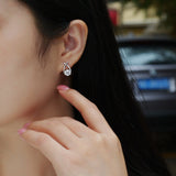 Worn stud earrings: teardrop moissanite with ribbon pavé, white gold vermeil finish