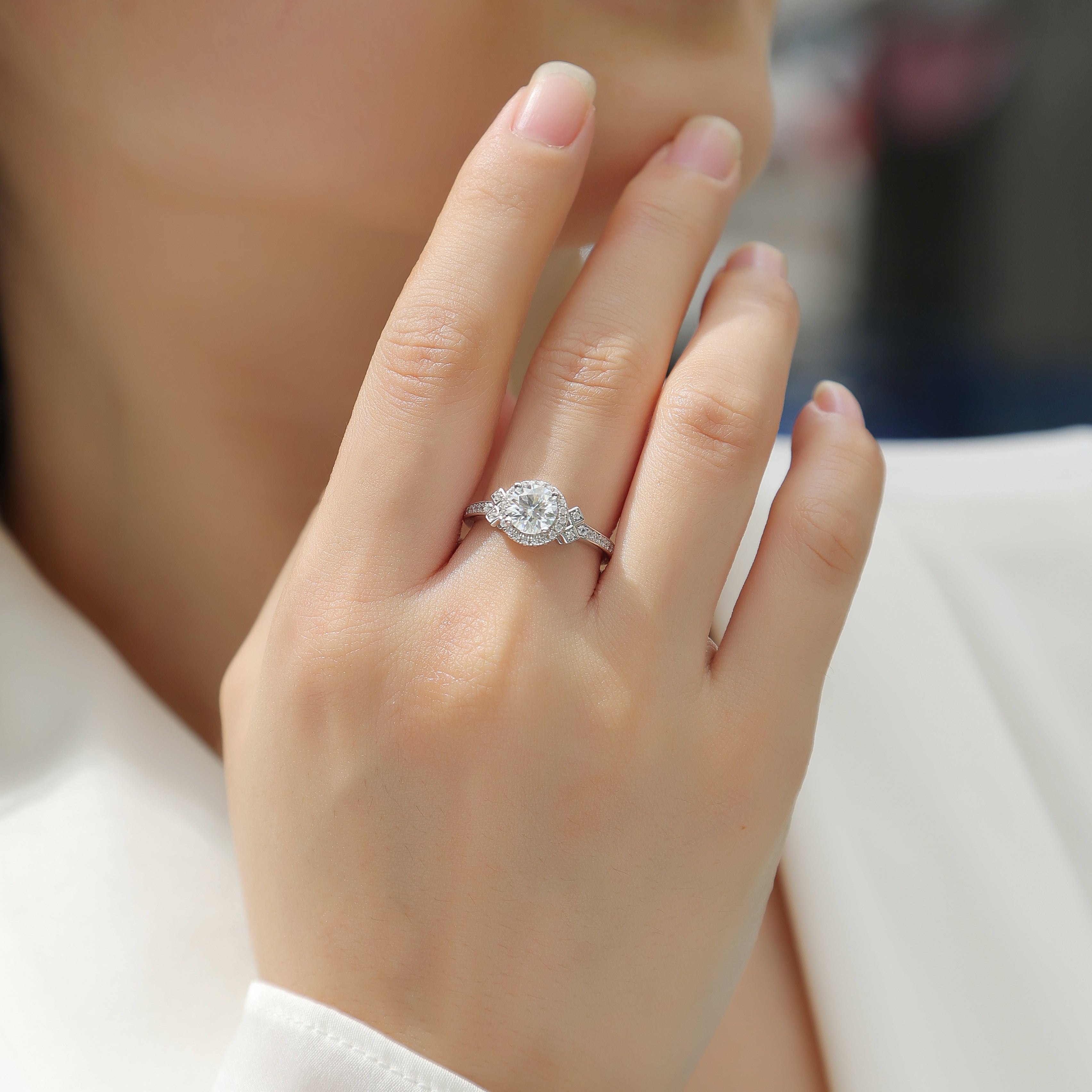 Hand wearing round halo art deco cross pavé ring with sparkling round center stone