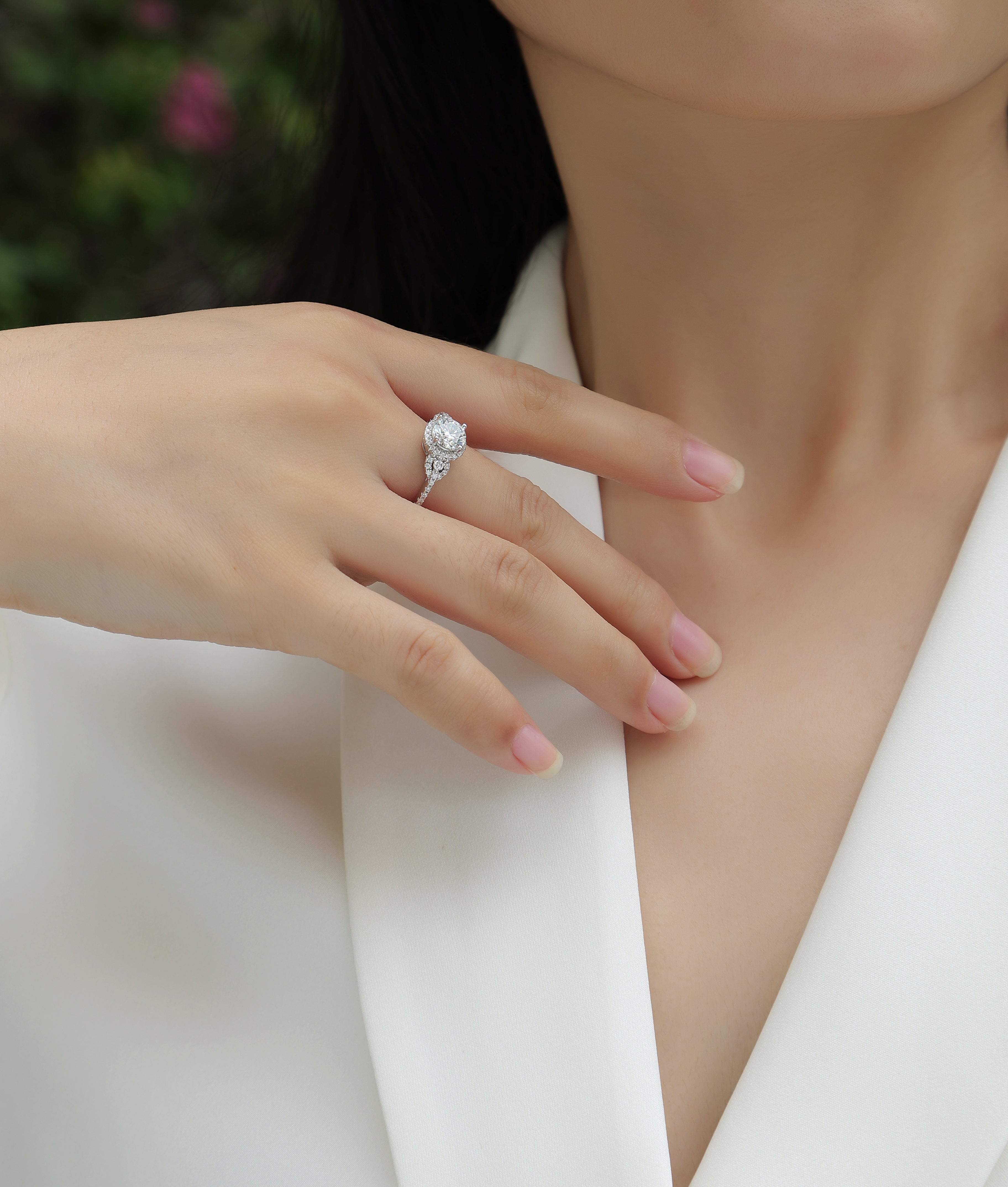 Ring on finger: round center stone with sparkling halo and pear side stones
