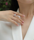 Ring on finger: round center stone with sparkling halo and pear side stones
