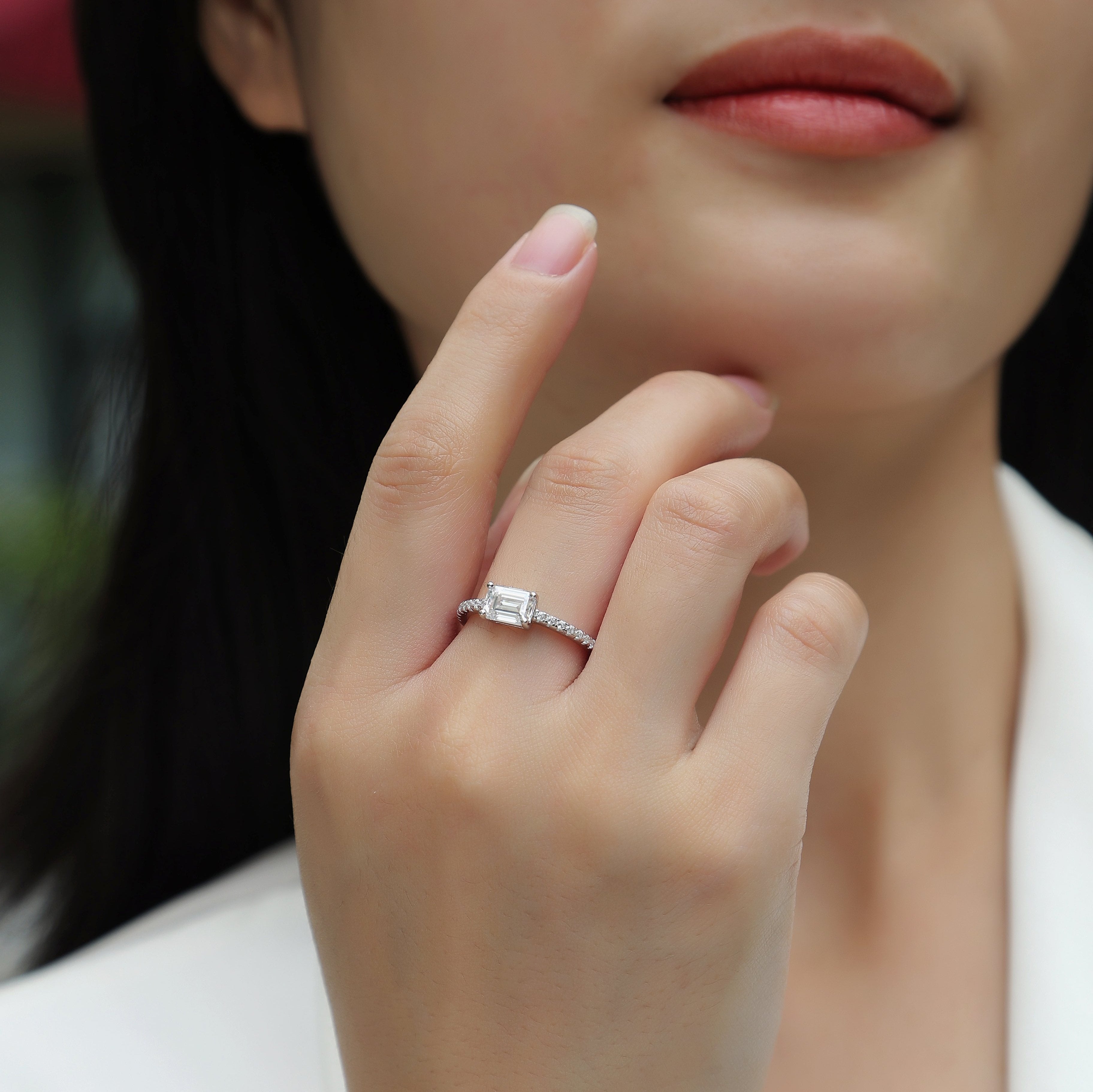 Emerald-cut moissanite pavé shoulder ring on hand, white gold tone, silver sparkle